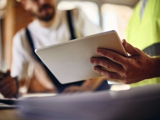 Two workers holding a tablet in a meeting on site