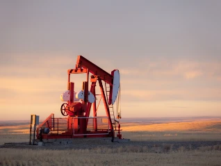 Pump jack in an oil field at sunset
