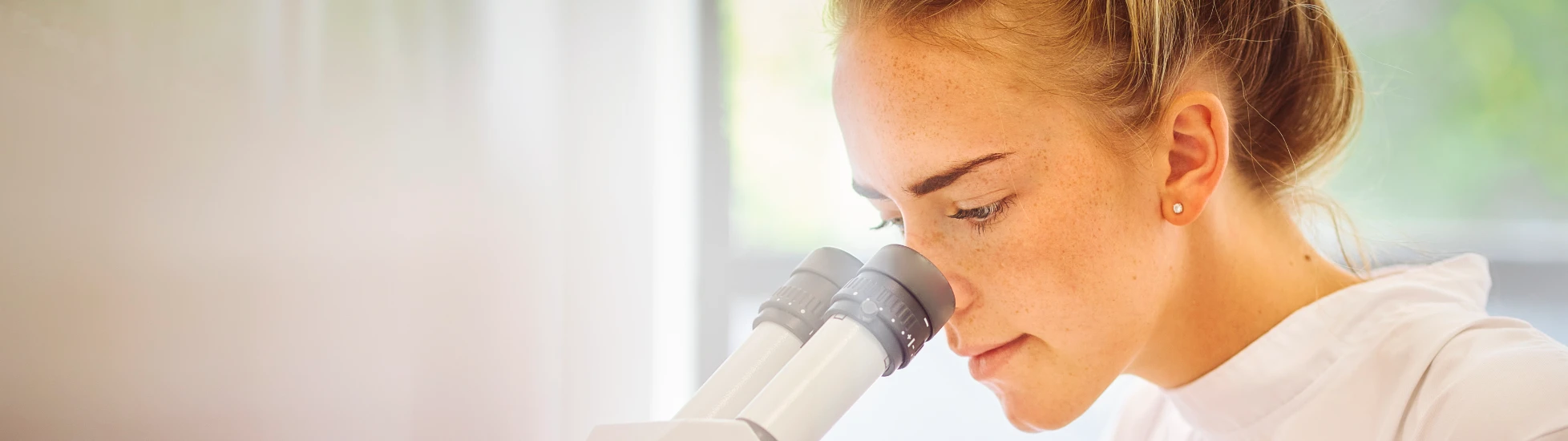 Young female pharmaceutical worker with microscope