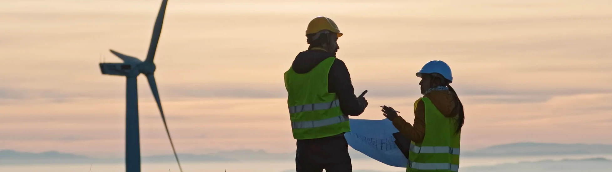 Two wind turbine engineers at sunset