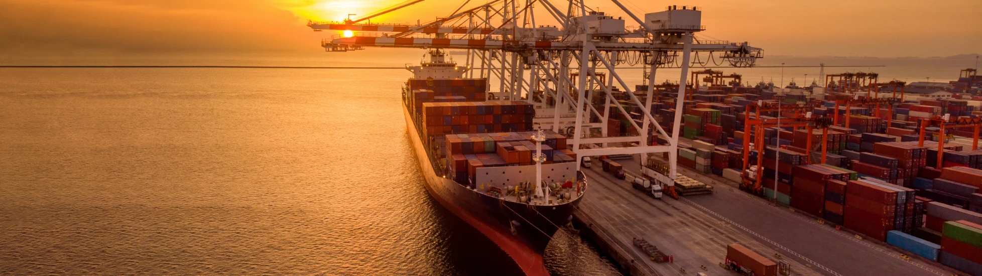 Crane loading container onto container ship at sunset