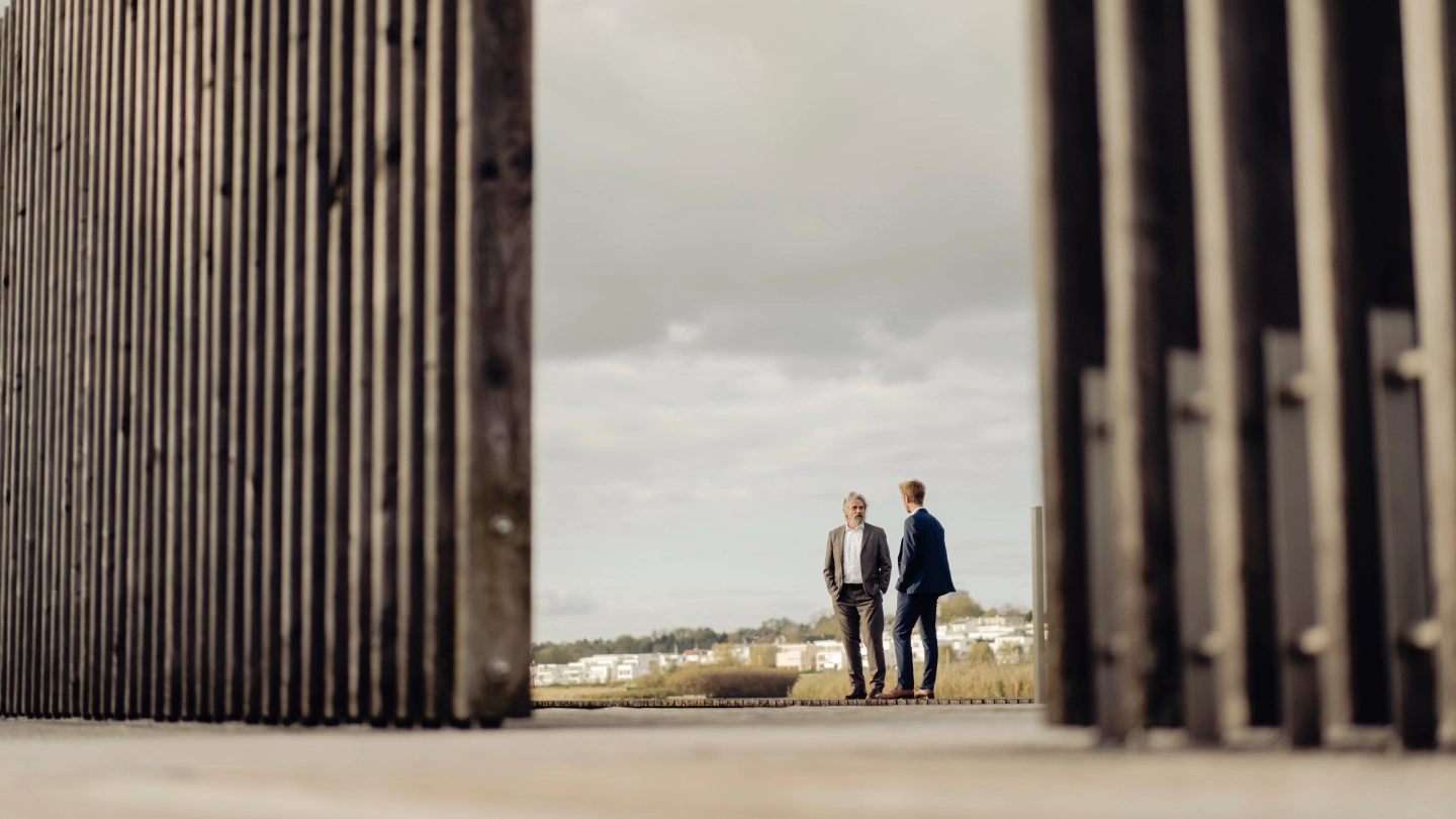 Two businessmen standing behind fencing image