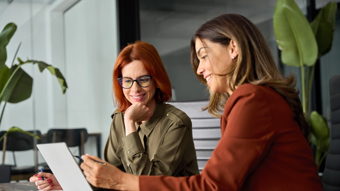 Two smiling young women reviewing work on a laptop image