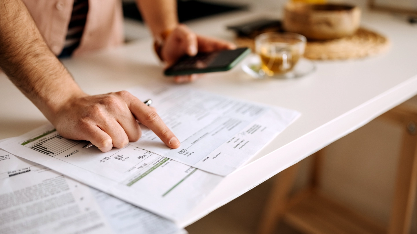 man pointing at sheet and holding mobile phone man pointing at sheet and holding mobile phone